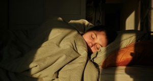Woman sleeping deeply in bed, reflecting on how women need more sleep than men